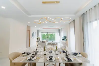 Luxurious dining room with elegant table setting and modern lighting in a spacious open-plan layout.