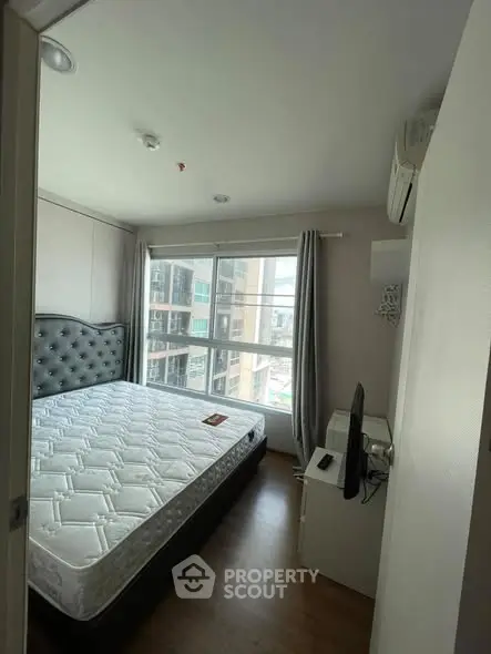 Cozy bedroom with large window and modern furnishings in urban apartment