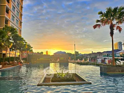 Stunning sunset view over a luxurious apartment pool with palm trees and skyline.
