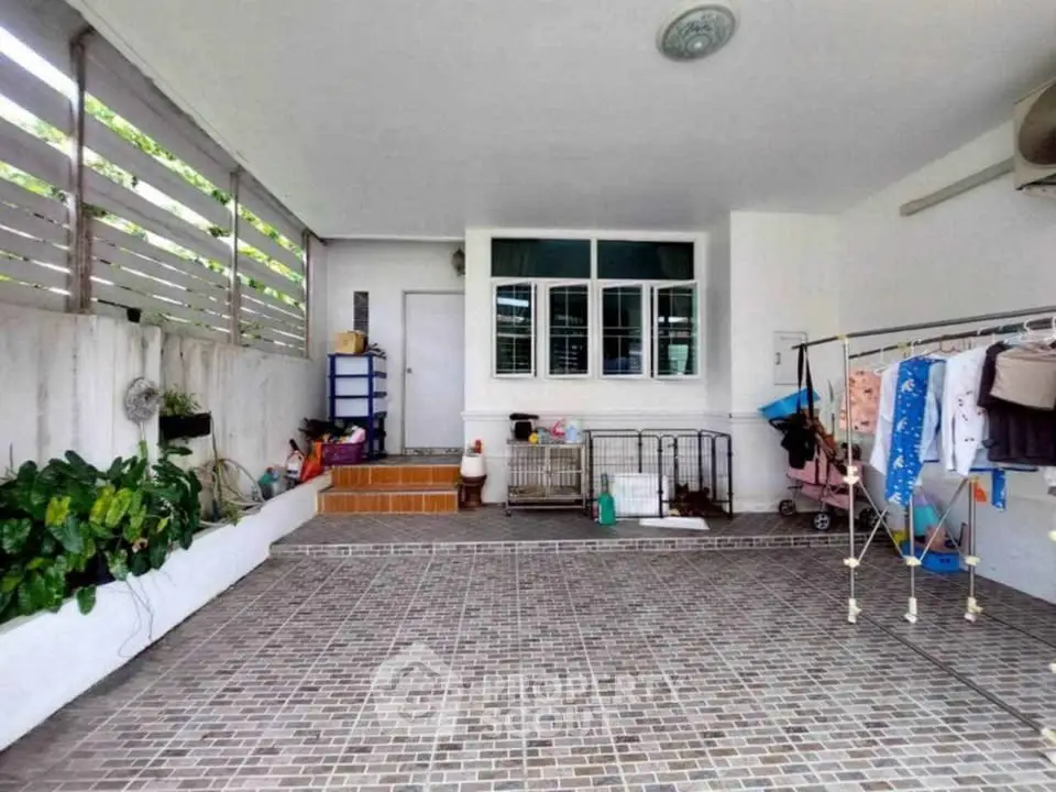 Spacious tiled patio with laundry area and greenery, perfect for versatile outdoor living.