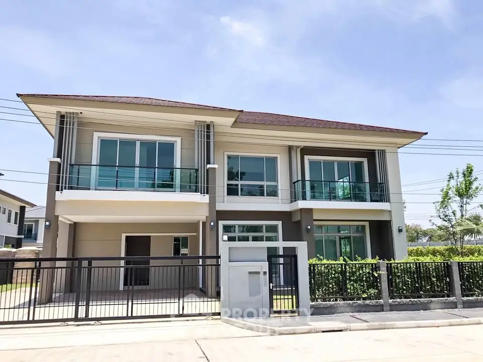 Modern two-story house with large windows and balcony in a serene neighborhood.