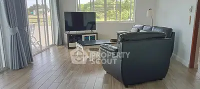 Spacious living room with large windows and modern furniture, offering a bright and inviting atmosphere.