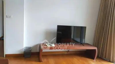 Minimalist living room with wooden floor and TV on a sleek table.