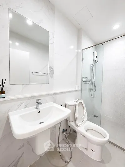 Modern bathroom with sleek fixtures and glass shower enclosure in a contemporary home.