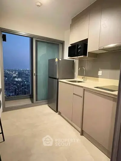 Modern kitchen with city view, featuring sleek cabinetry and stainless steel appliances.