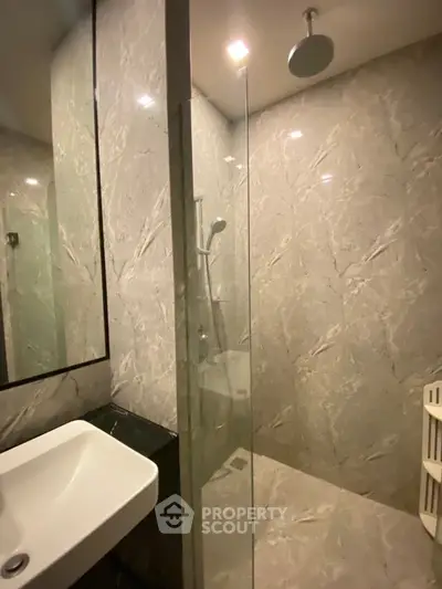 Luxurious modern bathroom with marble walls and glass shower enclosure