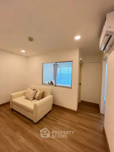Cozy living room with wooden flooring and a comfortable sofa, perfect for relaxation.
