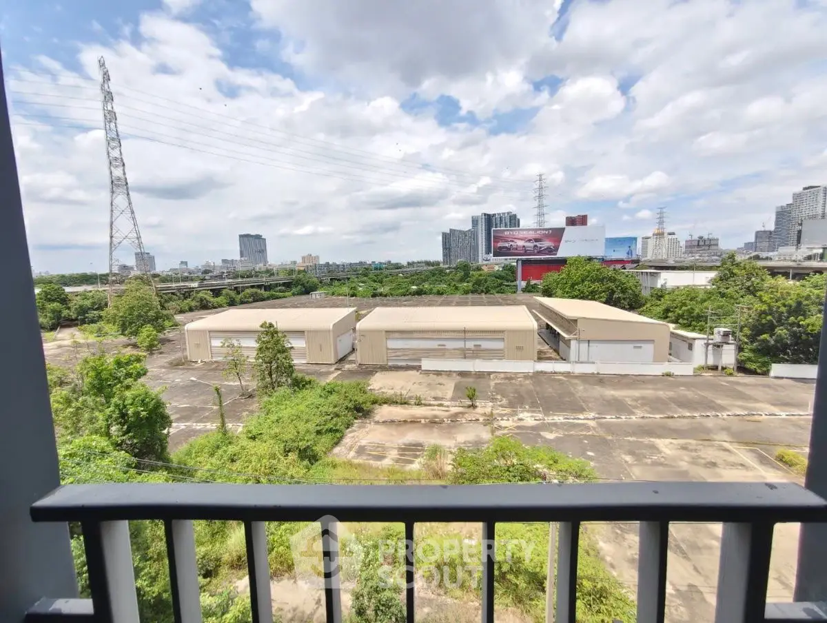Expansive industrial view from balcony overlooking warehouses and city skyline.