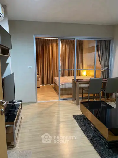 Modern apartment interior with open living room and bedroom, featuring sleek furniture and warm lighting.