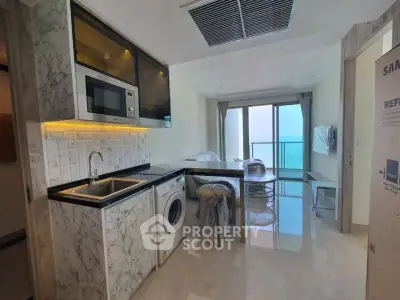 Sleek modern kitchen with marble countertops, stainless steel appliances, and a breathtaking ocean view from the adjoining balcony.