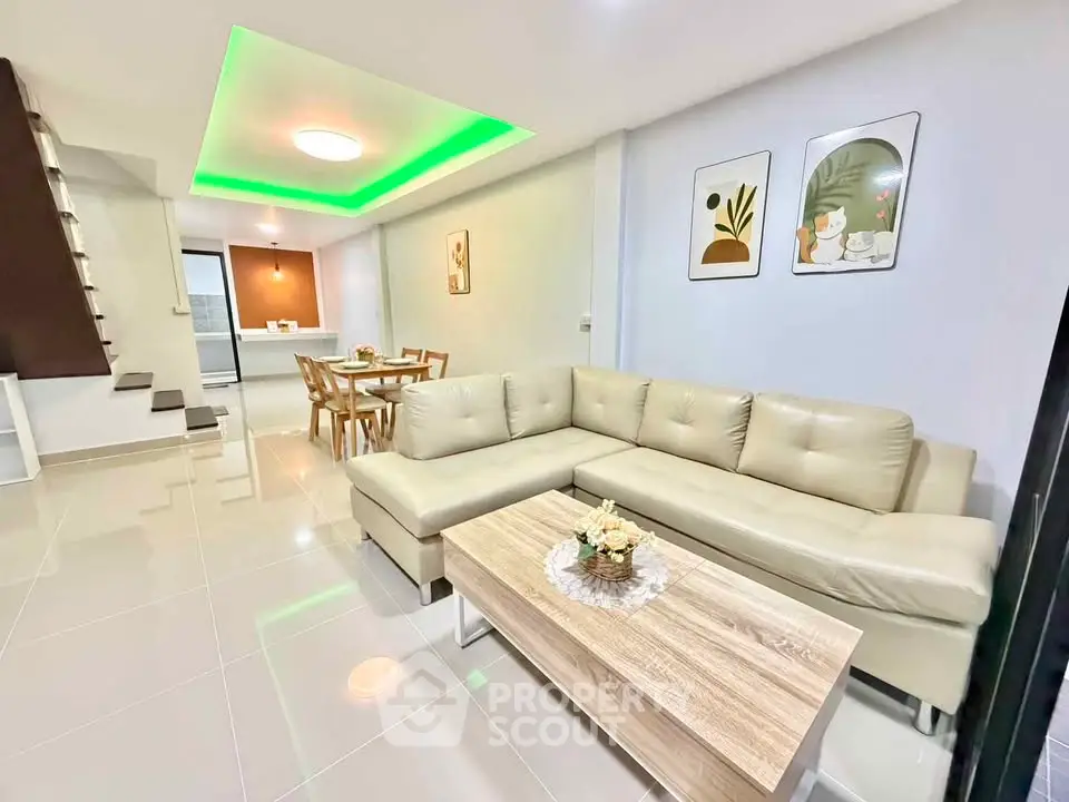 Modern living room with stylish decor and open dining area, featuring a cozy L-shaped sofa and elegant lighting.