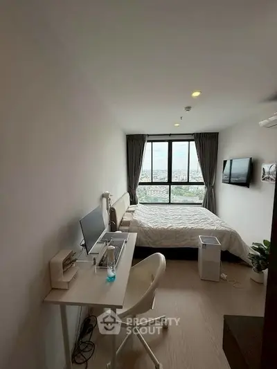 Modern bedroom with workspace and city view, featuring sleek furniture and large window.