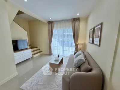 Modern living room with cozy sofa, stylish decor, and natural light from large window.