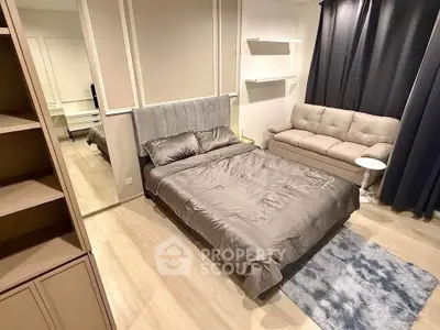 Modern bedroom with stylish decor, featuring a cozy bed, plush sofa, and elegant flooring.