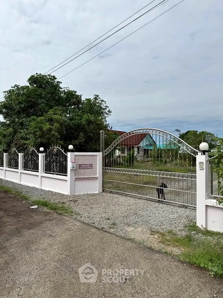 Charming gated entrance with lush greenery and spacious driveway, perfect for privacy and security.