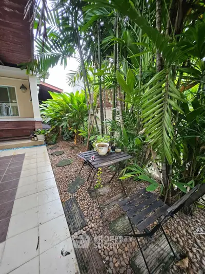 Charming garden patio with lush greenery and cozy seating area, perfect for relaxation and outdoor enjoyment.