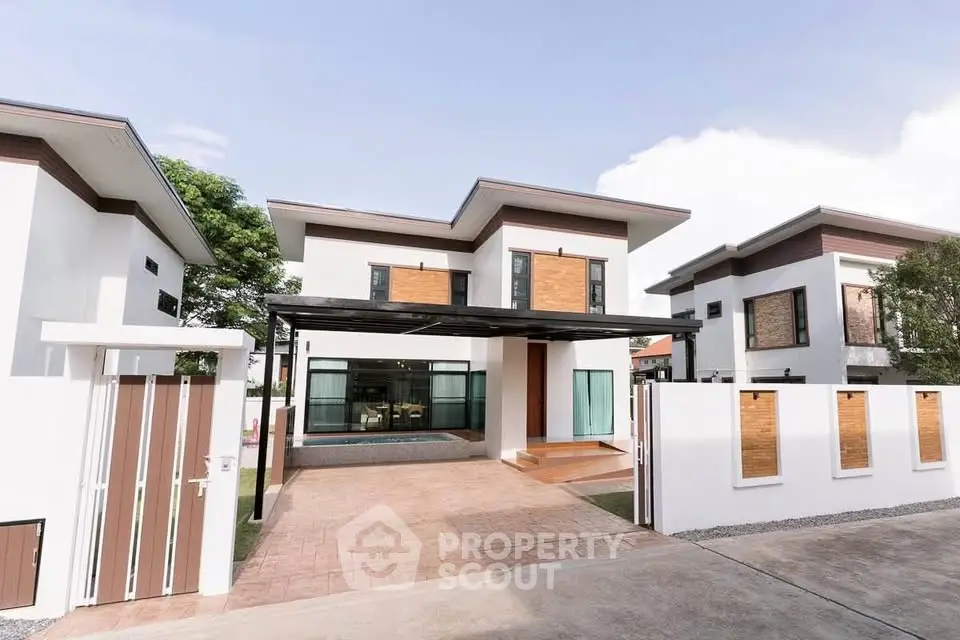 Modern two-story house with sleek design and spacious driveway in a suburban neighborhood.
