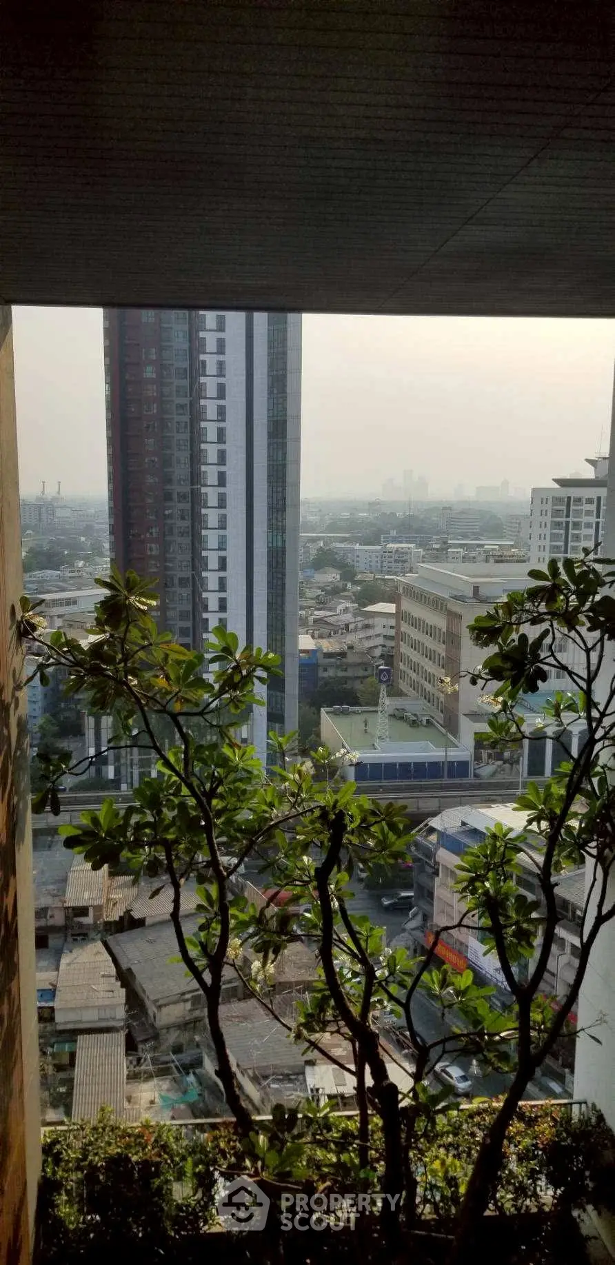 Stunning cityscape view from a high-rise balcony with lush greenery.