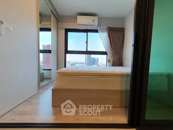 Modern bedroom with large window and city view, featuring air conditioning and stylish decor.