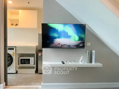 Modern living space with TV, washing machine, and microwave under staircase