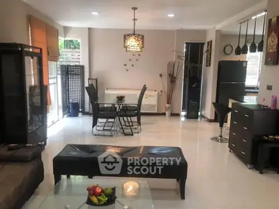 Spacious modern living room with dining area and sleek kitchen, featuring elegant decor and natural light.