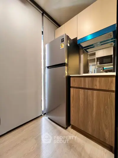 Modern kitchen with sleek fridge and stylish cabinetry in a contemporary apartment.