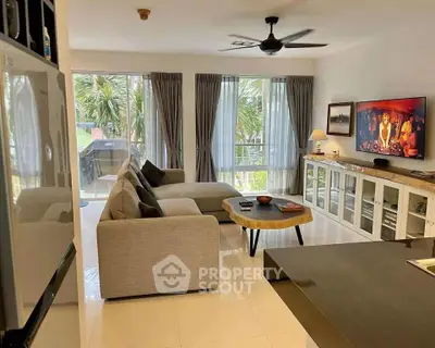 Spacious living room with modern decor and large windows overlooking greenery.