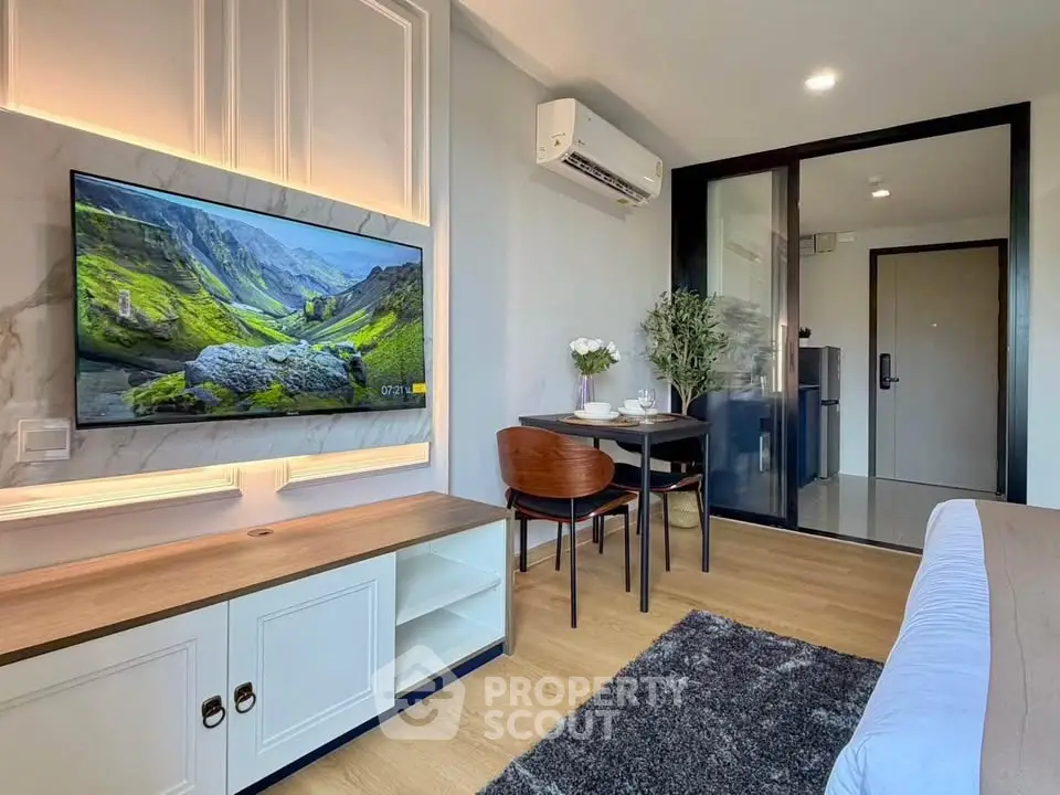 Modern living room with stylish decor, wall-mounted TV, and dining area in a cozy apartment.