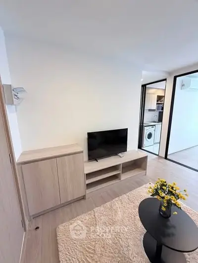 Modern living room with TV, light wood furniture, and cozy decor in a stylish apartment.