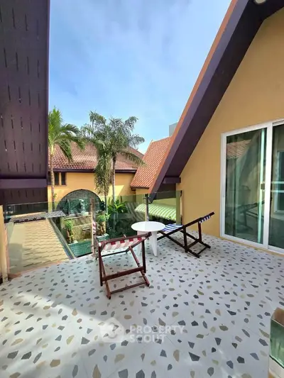 Charming balcony with seating, offering a serene view of lush greenery and unique architecture.