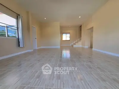 Spacious empty living room with tiled flooring and natural light