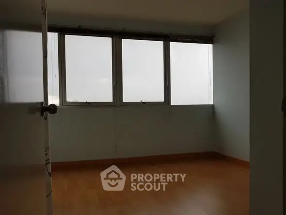 Spacious empty room with large windows and wooden flooring, ideal for customization.