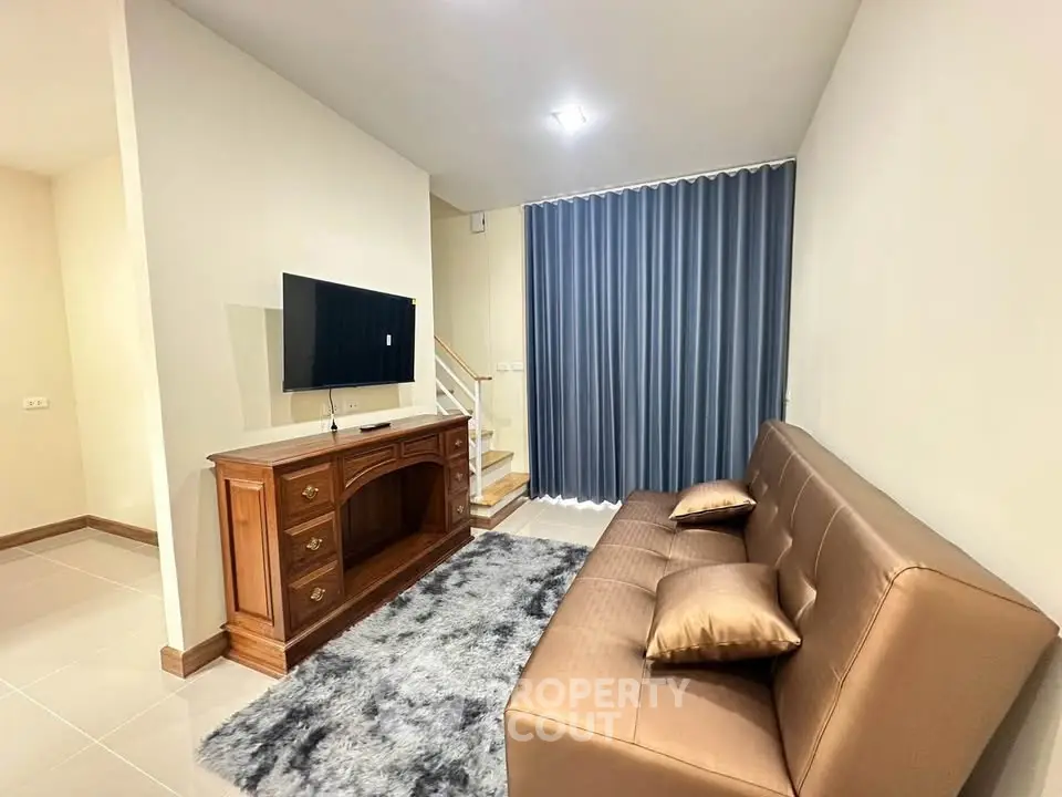 Modern living room with sleek sofa, TV, and elegant decor in a cozy setting.