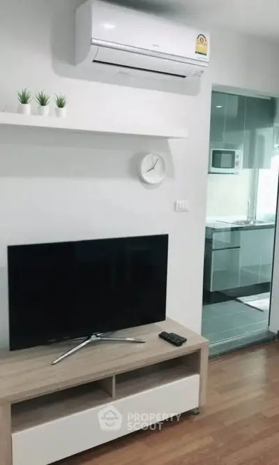 Modern living room with sleek TV stand, air conditioning, and view into stylish kitchen.