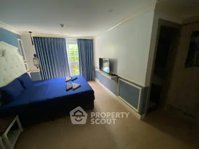 Spacious bedroom with elegant blue decor and natural light from large window.