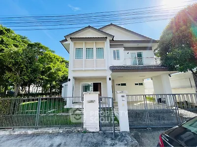 Charming two-story house with lush garden and gated entrance in a serene neighborhood.