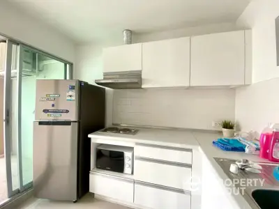 Modern kitchen with sleek white cabinets and stainless steel appliances in a bright apartment.