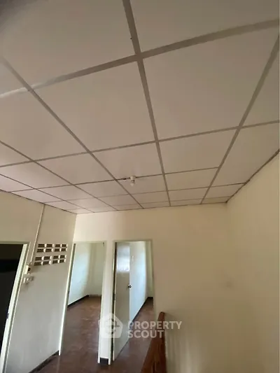 Spacious hallway with tiled ceiling and wooden flooring in a residential property.