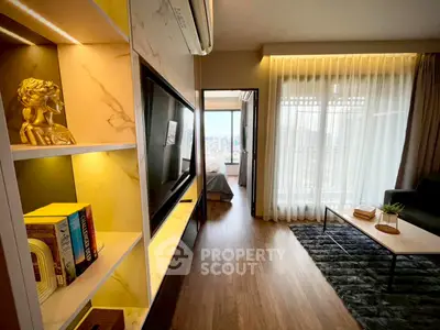 Stylish modern living room with open view to bedroom, featuring elegant decor and natural light.