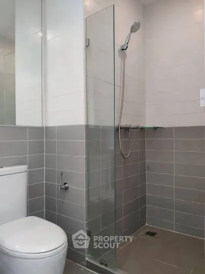 Modern bathroom with sleek shower and tiled walls in contemporary apartment.