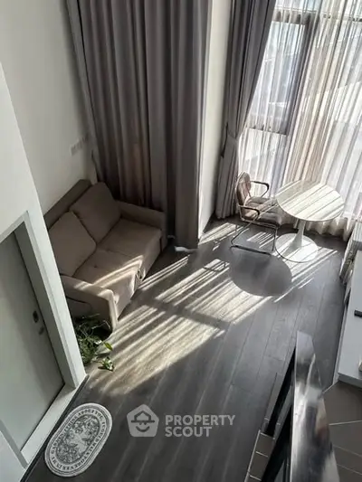 Modern living room with high ceilings, large windows, and stylish furniture in a contemporary apartment.