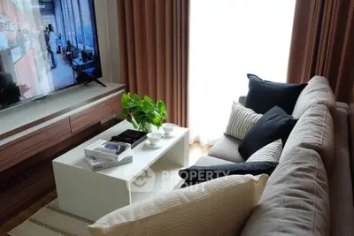 Cozy living room with modern decor, plush sofa, and flat-screen TV, perfect for relaxation.