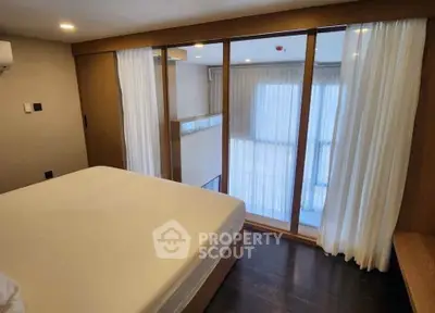 Modern bedroom with large windows and wooden accents, offering a cozy and inviting atmosphere.