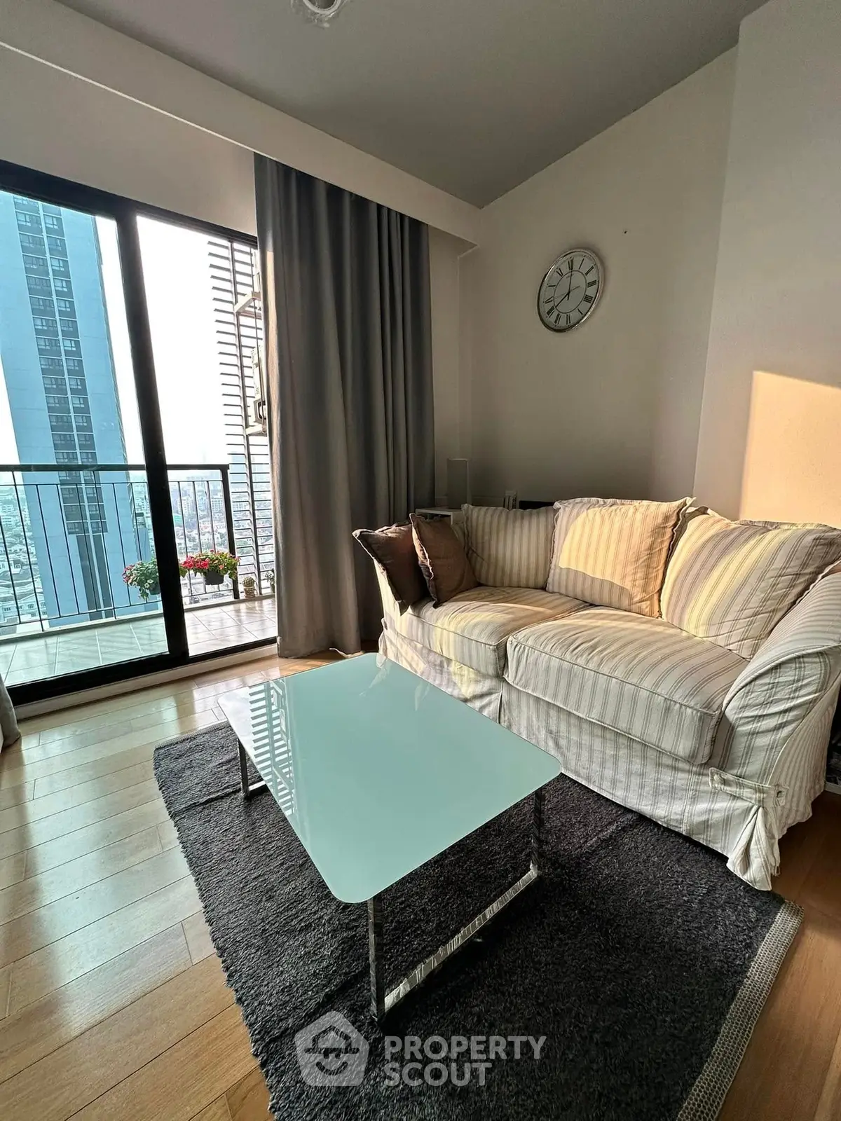 Chic living room with cozy sofa and glass coffee table, featuring a stunning city view from the balcony.