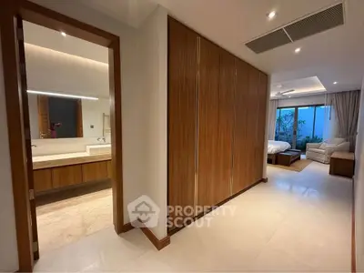 Spacious modern bedroom with ensuite bathroom and garden view, featuring elegant wooden accents and ample natural light.