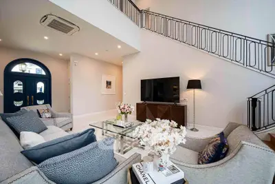 Luxurious living room with elegant decor and high ceilings, featuring a stylish staircase and modern furnishings.