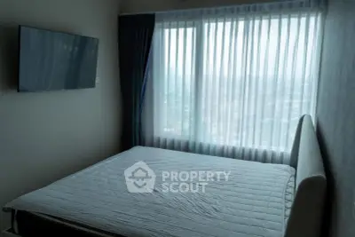 Modern bedroom with large window offering stunning city view and wall-mounted TV.