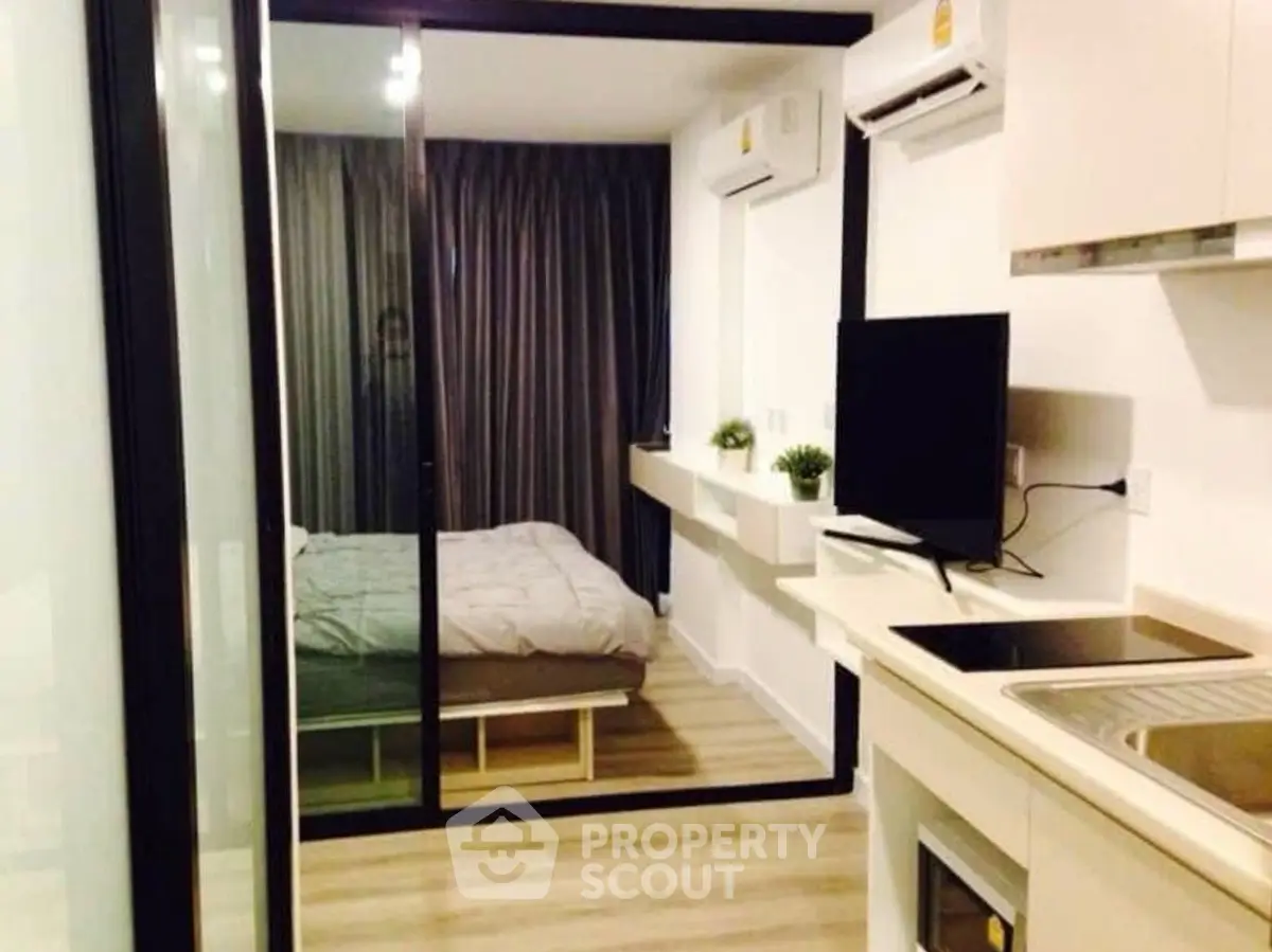 Modern studio apartment with glass partition, sleek kitchen, and cozy bedroom.