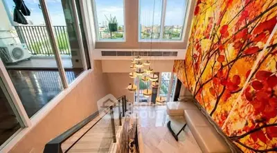 Luxurious duplex with stunning chandelier and vibrant wall art, featuring a spacious balcony with city views.