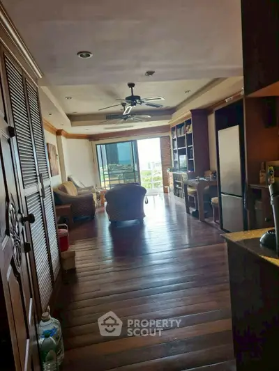 Spacious living room with wooden flooring and balcony view in modern apartment.
